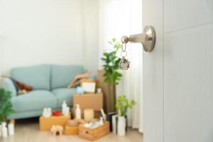 Moving house, relocation. The key was inserted into the door of the new house, inside the room was a cardboard box containing personal belongings and furniture. move in the apartment or condominium. photo