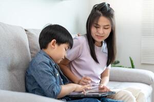 mother playing teach using tablet with the little boy. family is happy and excited in the house. mother and son having spending time together, Good daddy , addiction fix, handle, control photo
