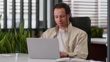 Ethnic American business man hipster businessman guy male worker in office programmer manager working computer online typing laptop at workplace table smiling happy looking at camera job work startup video