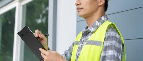 inspector or engineer is inspecting construction and quality assurance new house using a checklist. Engineers or architects or contactor work to build the house photo