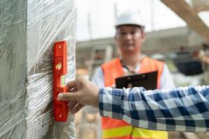 Contactor or engineer is inspecting construction and quality assurance new house using a level. Engineers or architects or contactor work to build the house before handing it over to the homeowner. photo
