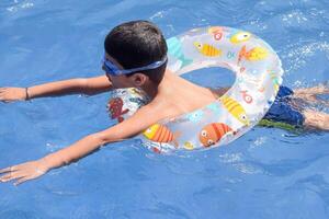 A young boy floating in a pool with an inflatable ring photo