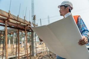 engineer is inspecting construction and quality assurance new house using a blue print. Engineer or architects or contactor work to build the house before handing it over to the homeowner, photo