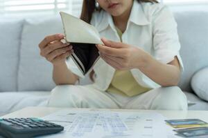 Stressed and headache asian woman with large bills or invoices no money to pay to expenses and credit card debt. shortage, Financial problems, mortgage, loan, bankruptcy, bankrupt, poor, empty wa photo