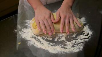 Detailed close-up of hands pressing and kneading soft dough, fingers lightly coated in flour. The dough appears fluffy and elastic, emphasizing the tactile process of baking. The warm, golden kitchen video