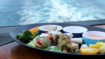 breakfast on a liner against the backdrop of the water of a departing ship delicious kebabs of fish meat various sauces with vegetables beautiful view luxury rest video