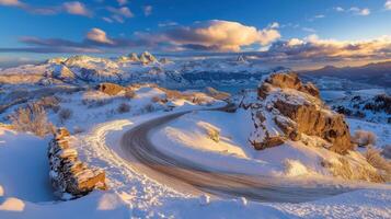 A winding road in the snow with mountains in the background photo