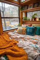 A bed with a blanket and pillows under a window photo