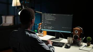 African american expert at desk using pc for programming and data analysis. Young networking expert working from his home setup, manages information technology and data center. Camera A. video