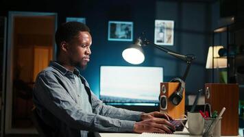 Black developer feeling exhausted and trying to meet task deadline, working hard to finish report in time and dealing with a headache. African american guy being under stress with pressure. Camera A. video