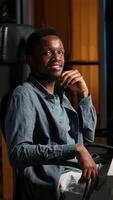 Vertical Black young adult working remotely and organizing information, reviewing notes and making data driven decisions to complete his freelancing tasks. Managing his schedule efficiently. Camera B. video
