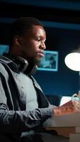 Vertical African american guy does remote work and engaging in a web conversation, using his laptop to attend an online call meeting in his living room. Young man joining a conference. Camera A. video