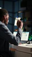 Vertical Black man organizing his schedule with a planner and putting a reminder, creating an adhesive note post it and browsing the web. Modern productive guy writes a memo for research. Camera A. video