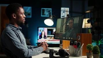 African American man enjoys conferencing with manager at desk, discussing with his colleague online using a computer at home office setup. Young associates team meeting online. Camera A. video