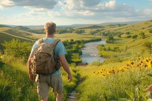 Man with backpack walking through grassy hillside with sunflowers photo