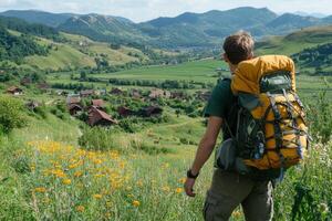 A man with a backpack looking at a village photo