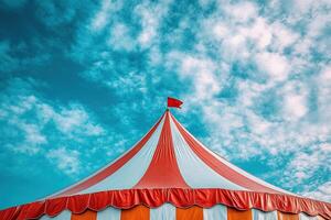 The roof of a circus tent in red and white stripes against a blue sky. photo