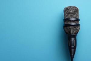 Microphone with elegant design and silver mesh head and black body, ideal for performances, recording and public speaking. Microphone on a blue background with copy space. photo