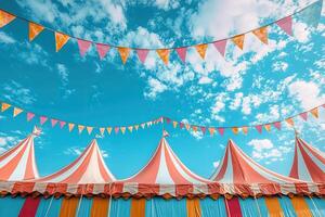 The roof of a circus tent with a red and white striped pattern against a blue sky and several garlands of flags. Circus Day. photo