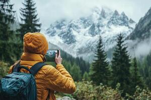 A female tourist in a yellow jacket and with a backpack on her back takes a photo on a smartphone in the mountains. A female tourist during her vacation.