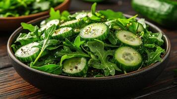 A bowl of greens with cucumbers and herbs photo