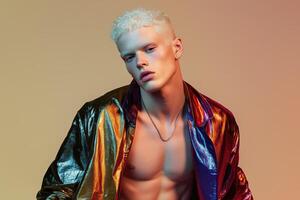 Stylish avant-garde albino male model with platinum blonde hair wearing a metallic iridescent jacket under dramatic lighting photo