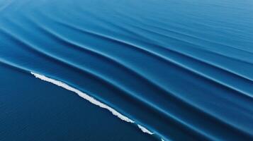Aerial view of smooth ocean waves rolling in rhythmic patterns with deep blue water and white foam photo