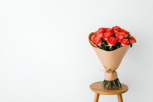 Elegant bouquet of red roses on wooden stool photo