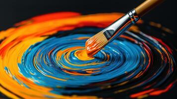 Close-up of a paintbrush blending vibrant blue, orange, and yellow acrylic paint in a swirling abstract pattern photo