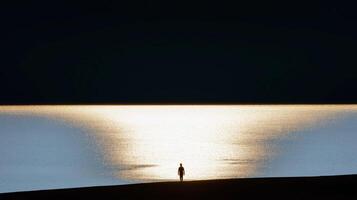 Silhouette of a person standing near a calm lake with golden sunset reflection creating a serene and dramatic contrast photo