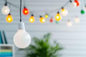 Close-up of a white light bulb with colorful string lights blurred in the background indoors photo