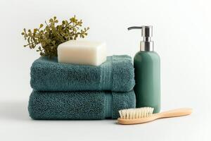 Spa essentials with stacked green towels wooden brush soap bar pump bottle and greenery on white background photo