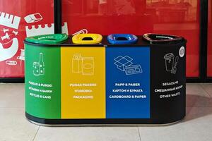 Set of four color-coded recycling bins labeled for bottles, packaging, paper, and mixed waste, promoting environmental awareness and proper waste disposal in public area. Narva, Estonia - 06.07.2021 photo