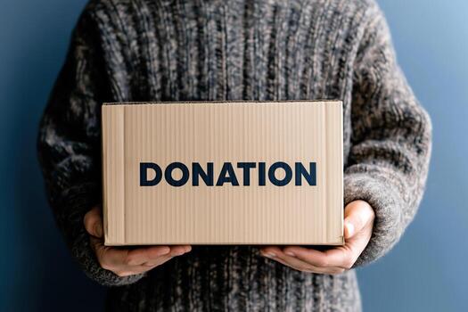 Close-up of hands holding a cardboard donation box with the word donation printed on it photo