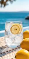 Refreshing Glass of Ice Water with Lemon Slices on a Sunny Patio by the Ocean photo