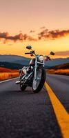Vintage Motorcycle Parked on Open Road at Sunset with Scenic Mountain View and Dramatic Sky photo