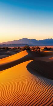 Stunning Desert Dunes Illuminated by Golden Sunset with Gradient Sky and Distant Mountains photo