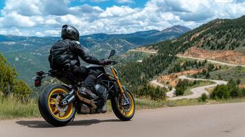 Motorcyclist in black leather gear enjoying scenic mountain views on a winding road photo