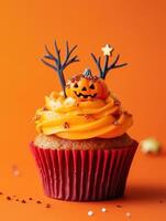 Halloween-Themed Cupcake with Pumpkin Topper on Bright Orange Background photo