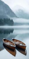 Two wooden boats sit on the water in front of a mountain photo