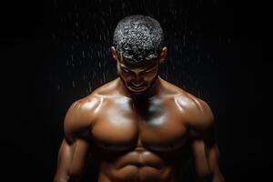 Muscular man in the shower with water running down his body photo