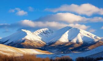 Snow-capped mountains under a blue sky with scattered clouds. photo