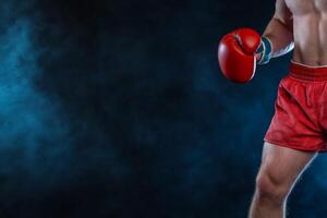 A boxer in red shorts and gloves, poised for action against a dark backdrop. photo