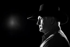 A man in a cowboy hat is looking away from the camera photo