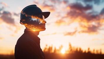 A silhouette of a person with a reflective helmet against a sunset sky. photo