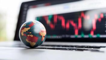 Globe on laptop with financial graphs in the background. photo