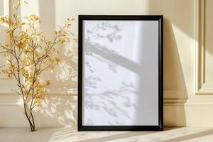 A blank picture frame beside a decorative branch, casting shadows. photo