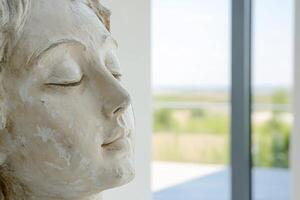 A serene sculpture with a tranquil expression, set against a natural backdrop. photo