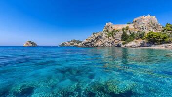 Serene coastal view with clear water and a historic fortress. photo