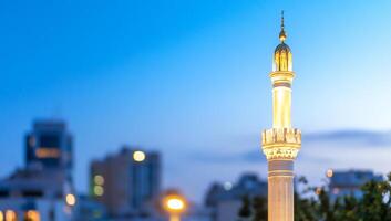 A minaret illuminated against a twilight city skyline. photo